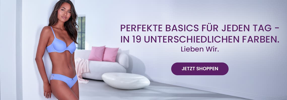 Perfekte Basics für jeden Tag in 19 Farben – Frau in hellblauem BH und Slip steht im Wohnzimmer neben Sofa mit Kissen