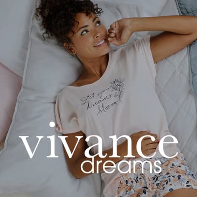 vivance dreams – Frau in hellem Pyjama liegt entspannt auf einem Bett