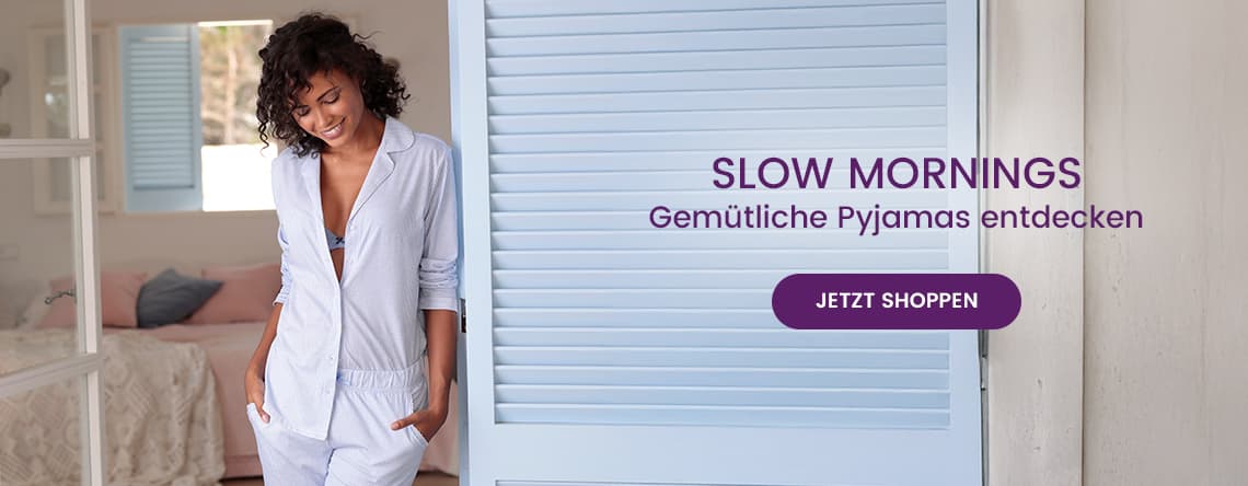 SLOW MORNINGS – Gemütliche Pyjamas entdecken – Frau in hellblauem Pyjama steht im Schlafzimmer