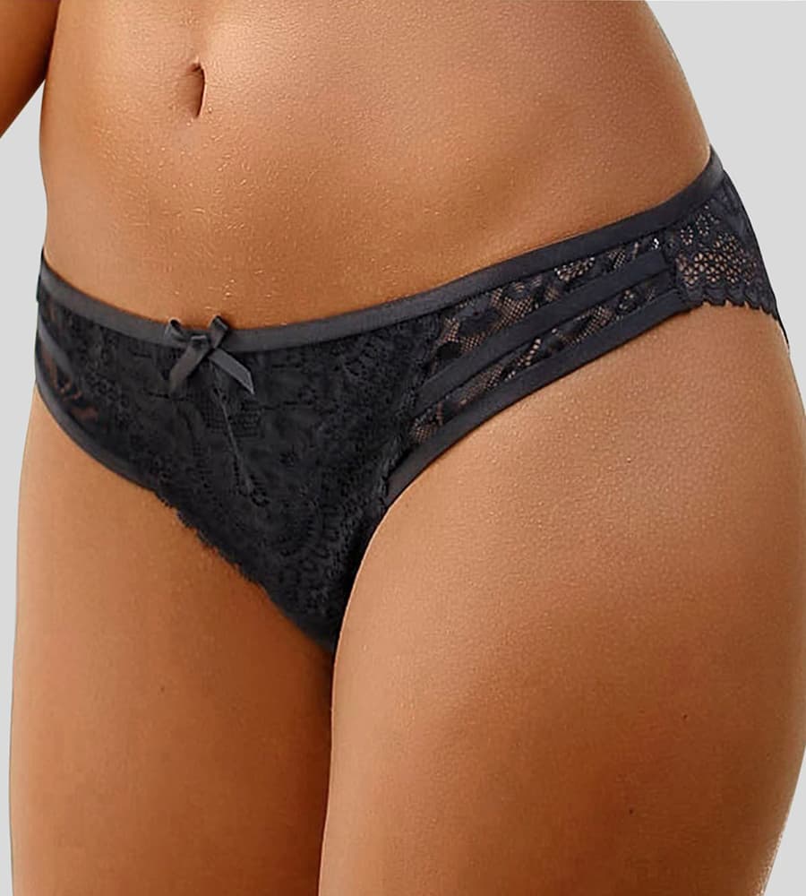 Schwarzer Spitzen-Slip mit kleiner Schleife vorne, getragen von einem Model vor grauem Hintergrund