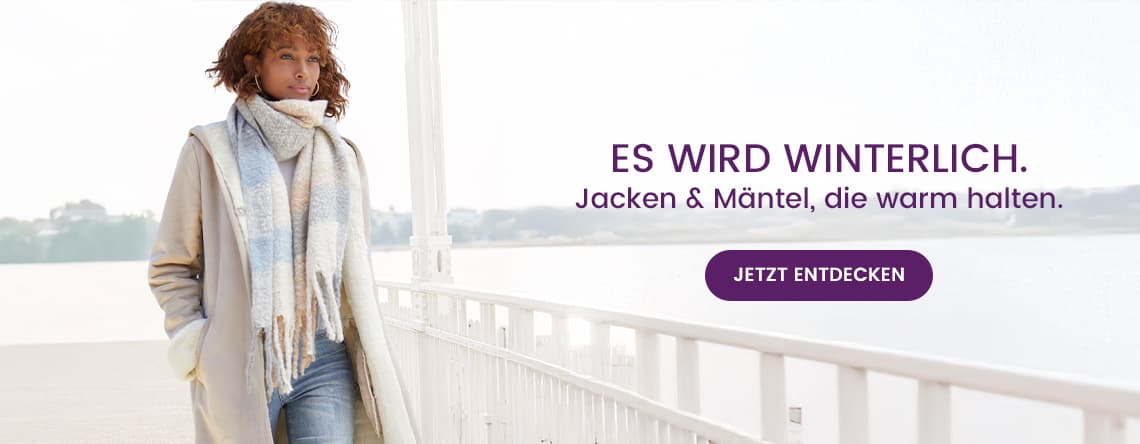Es wird winterlich. Jacken & Mäntel, die warm halten – Frau in Mantel und Schal spaziert entlang eines Geländers am Wasser