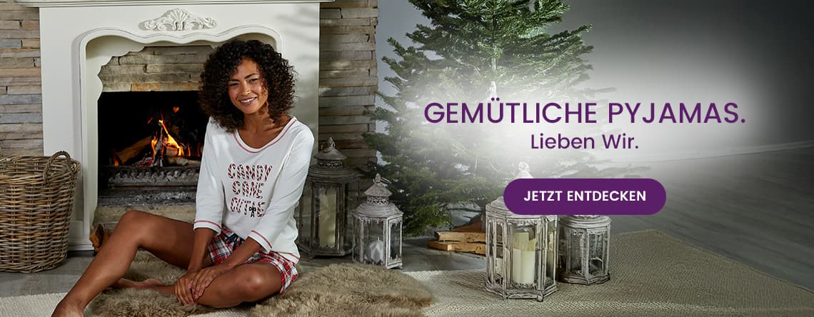 GEMÜTLICHE PYJAMAS. Lieben Wir. Frau im Pyjama sitzt vor Kamin neben Weihnachtsbaum. Jetzt entdecken.