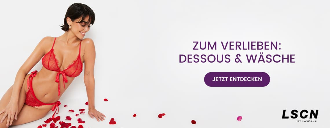 Zum Verlieben: Dessous & Wäsche – Frau in roter Spitzenunterwäsche liegt neben Rosenblättern auf weißem Hintergrund.