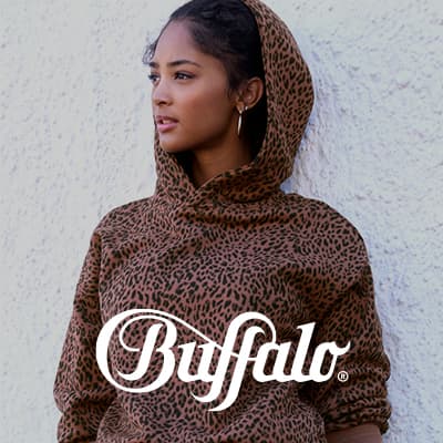 Buffalo Logo vor Frau im Leo-Hoodie, die seitlich blickend vor einer hellen Wand steht