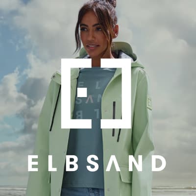 ELBSAND Logo vor Frau im hellen Regenmantel am Strand, darunter ELBSAND Schriftzug